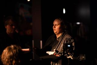 Crew member speaking during a discussion beside the camera