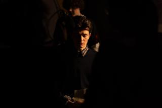 Actor standing in low light among the crew between takes