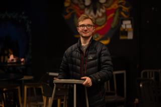 Crew member smiling while carrying a stool across the venue floor