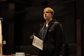 Crew member standing with a script in hand, looking toward the set