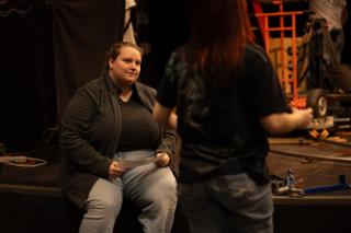 Two crew members talking beside the stage edge during a reset
