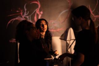 Crew conferring around a camera in front of a mural