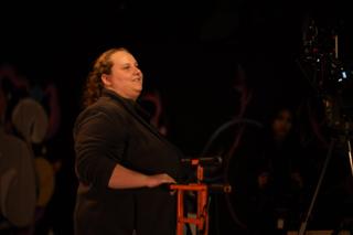 Crew member standing beside the camera, watching the stage