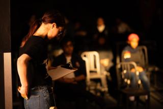Crew member reading from a clipboard, rows of empty chairs receding behind