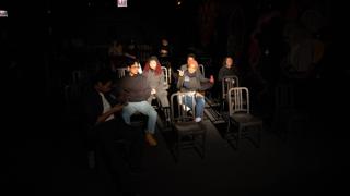 Crew talking among the rows of chairs, a painted mural on the wall behind