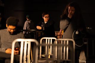 Crew at high tables during a break, one checking a phone