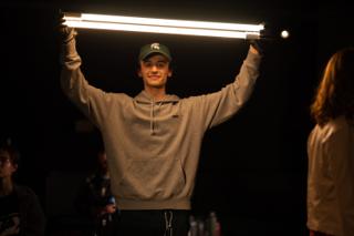 Crew member grinning as they hold a lit tube light above their head