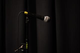 Close-up of a handheld microphone on its stand against the black stage curtain